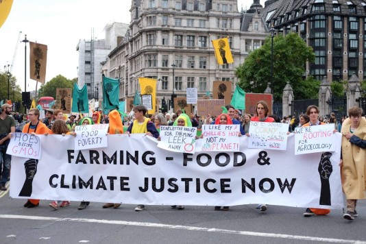 people marching in the streets with a banner 'farming - food & climate justice now'